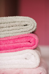 Stack of soft towels staying in bed in hotel room close up. Selective focus.