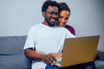 Portrait of an happy couple using a laptop computer in their house