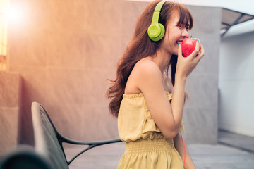 Euphoric woman listening music with Euphoric woman listening music with headphone and eating red apple beside swimmimngpool, happy and smile concept.headphone and eating red apple beside swimmimngpoo