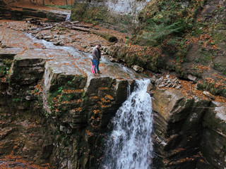 Obraz premium man holding usa flag on the top of the cliff autumn waterfall