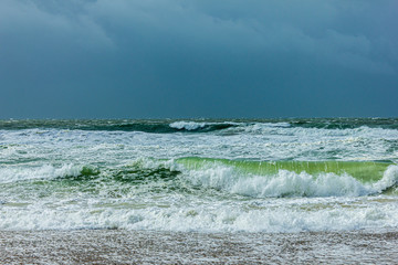 Huge crashing waves during a massive storm under a dark sky