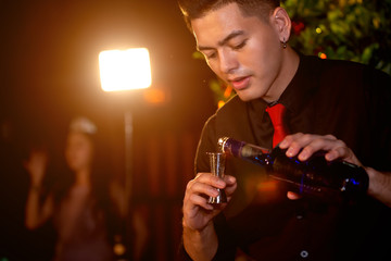 Professional bartender is making cocktail at night party.