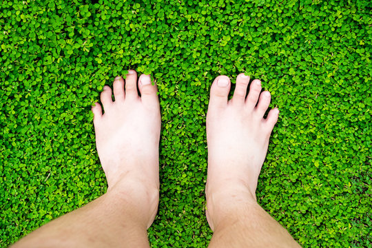 boy's feet standing on grass (Desmodium triflorum)