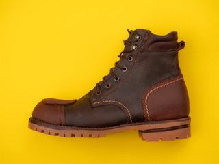Men fashion brown boot leather isolated on a yellow and red background. Top view