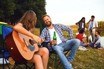 Friends with a guitar on a picnic on nature in autumn.