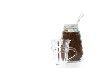 Empty crystal coffee mugs, coffee spoons and coffee in a glass bottle on a white background