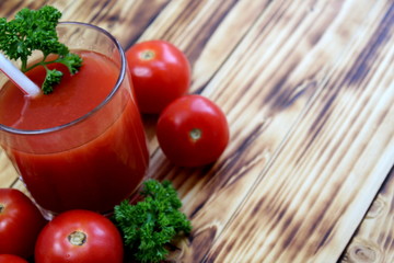 tomato juice in a glass with straws surrounded by tomatoes