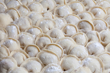 many handmade dumplings with meat shown close-up.