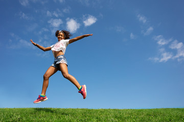 Girl jump and run over clean grass, sky background