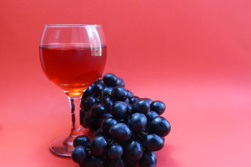 one glass of black grape wine on a red background