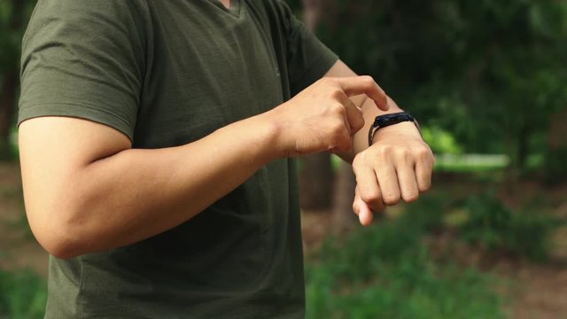 The hands of men are using smart watches to plan their workouts.