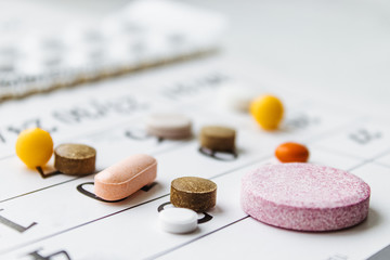 A bunch of different pills on a calendar background. Pills, supplements and medicines for the disease.