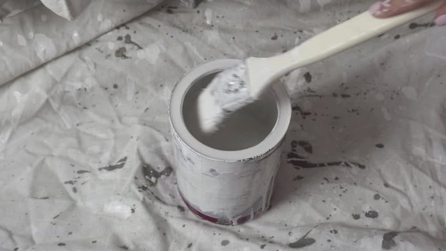 brush dipped in a jar of white paint