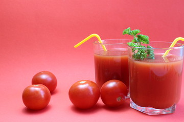 tomato juice in a glass with straws surrounded by tomatoes