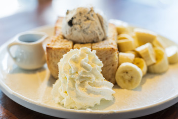 Close Up on, Honey Toast, Bread Buttered Toast, Banana, Ice Cream and Whipped Cream Dessert on a white Dish