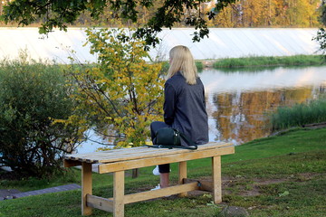 Fototapeta premium girl sits bored on a bench by the river