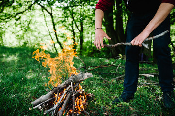 Naklejka premium Campfire on the nature. The branch is in the hands of man