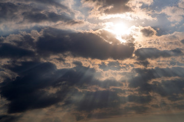 The rays of the sun make their way through dramatic thunderclouds