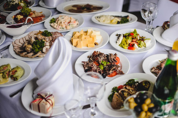 Wedding table, food, drinks, water..Table with silver and glass stemware at restaurant before starting to celebrate a wedding..Cheese, meat, salads. The holiday table
