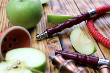 red hookah stands surrounded by green apple slices on a wooden