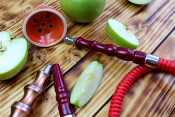 red hookah stands surrounded by green apple slices on a wooden