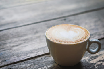 close up modern hot black coffee the cappuccino on wood background with coffee bubble foam pattern and texture in white cup looking and feel so delicious on glasses table in coffee shop.