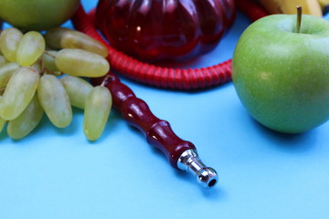 red hookah stands surrounded by fruit on a blue background