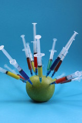 green apple studded with a multi-colored syringe
