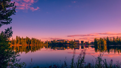 Obraz premium Sunset over Strbske pleso - tarn in High Tatras national park, Slovakia. There are trees and chalet reflections in the lake