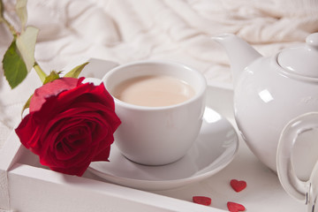 Close up of cup of tea with red rose on the white tray