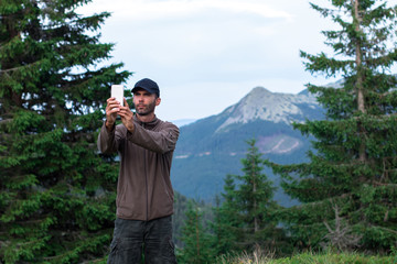 hiker man in cap making selfie in front of mountain range in the carpathian mountains gorgany