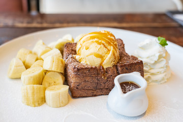 Close-up on, Honey Toast, bread buttered toast, banana, ice cream and whipped cream dessert on a white dish
