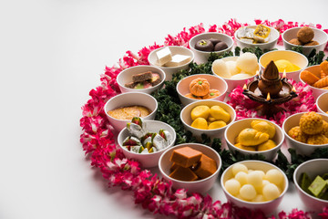 Flower Rangoli with sweets/mithai and diya in bowls for Diwali or any other festivals in India, selective focus