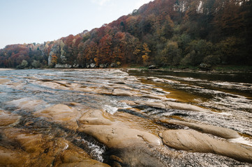 Clear river with rocks leads towards mountains..lit by sunset. Mountain fast flowing river stream of water in the rocks with blue sky. Landscape with forest, river and stones. The mountain river.