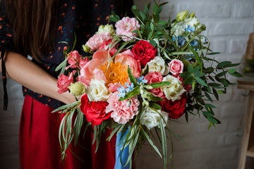 Floristic concept, business concept, gift, surprise, peonies, roses, carnations.  A large multi-colored bouquet stands on a chair. Peony, roses, carnations, eucalyptus, greens, garden flowers