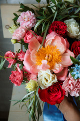 Floristic concept, business concept, gift, surprise, peonies, roses, carnations.  A large multi-colored bouquet stands on a chair. Peony, roses, carnations, eucalyptus, greens, garden flowers