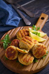 Fish cakes with lemon and herbs. Fish patties on wooden board