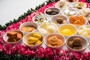 Flower Rangoli with sweets/mithai and diya in bowls for Diwali or any other festivals in India, selective focus