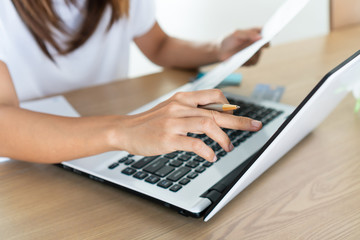 Woman holding saving account passbook and using computer laptop, account and saving concept.