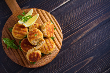 Fish cakes with lemon and herbs. Fish patties on wooden board. Overhead, horizontal image
