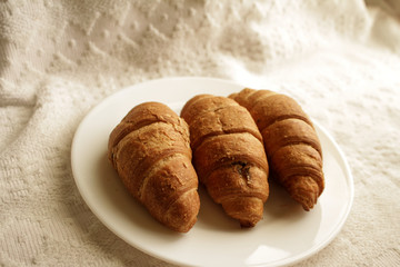 .croissants in a plate on a light background in a warm room in the morning