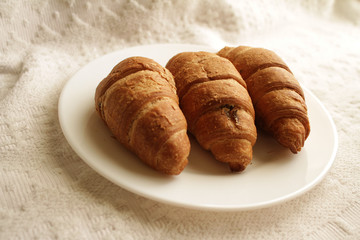 .croissants in a plate on a light background in a warm room in the morning