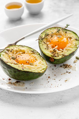 Tasty and healthy avocado snack. Slices of avocado with raw yolk, cheese, olive oil and spices on a white plate close-up.