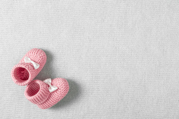 Baby pink shoes for newborn girl on knitted gray plaid. Flat lay, top view, copy space