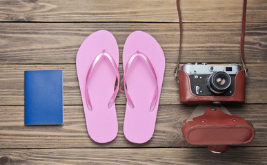 The concept of vacation on the beach, tourism. Summer traveler background. Flip flops, retro camera, passport on wooden background. Top view. Flat lay