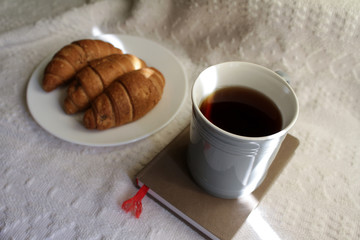 .breakfast with coffee and croissants, on a light background with a notebook