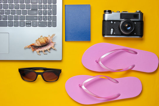 Summer leisure. Summertime relax.Laptop and travel accessories on yellow background. Studio short. Beach object. Top view. Flat lay