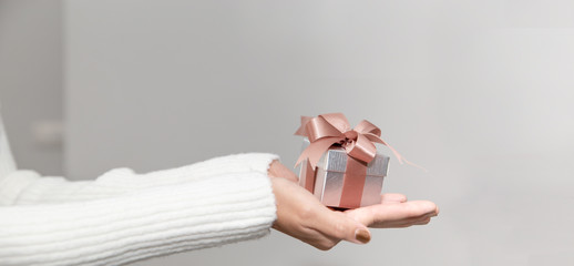Woman hands with white sweater holding a small gift box for special event with copy space.