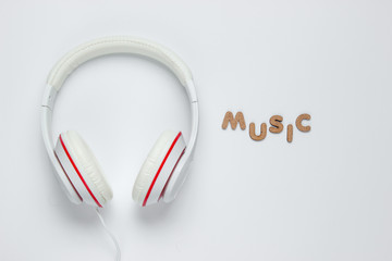 Classic white wired headphones on white paper background. Retro style. 80s. Pop culture. Top view. Word music