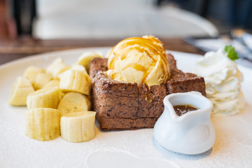 Close-up on, Honey Toast, bread buttered toast, banana, ice cream and whipped cream dessert on a white dish